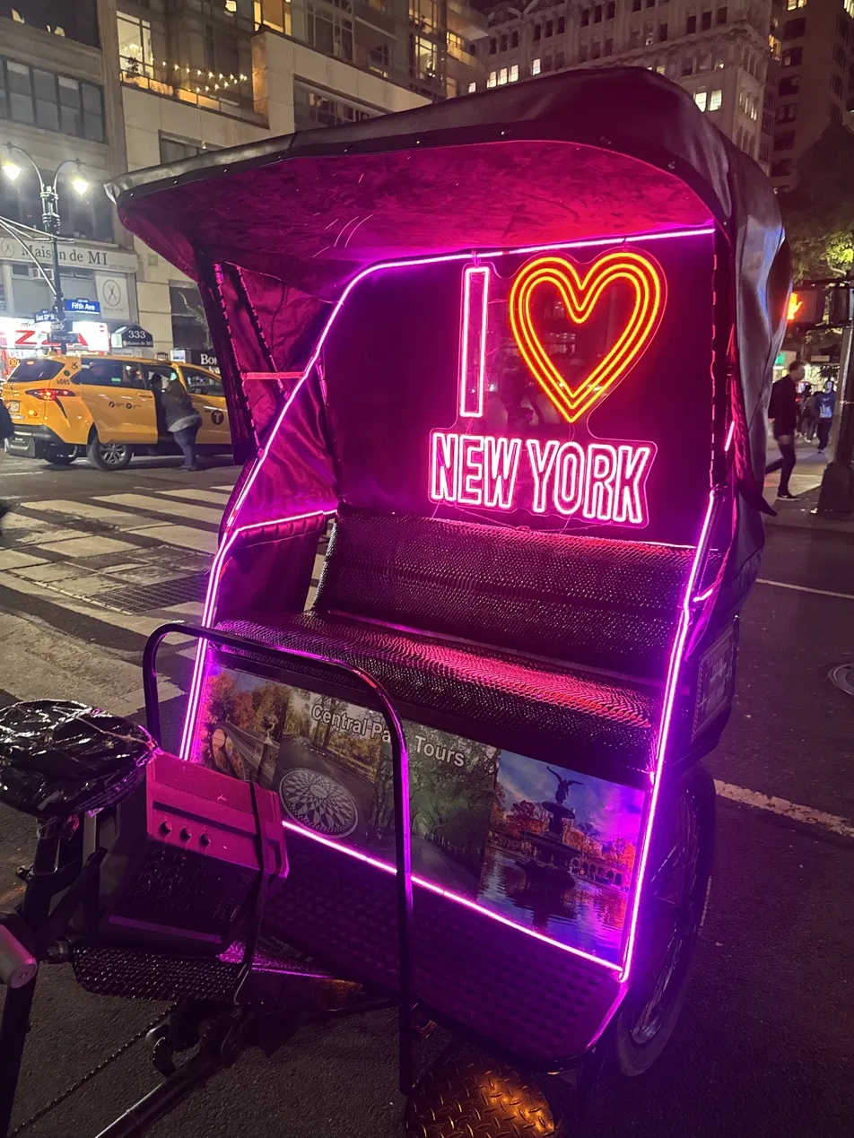 Pedicab with a neon I love New York sign on a Midtown Manhattan street at night